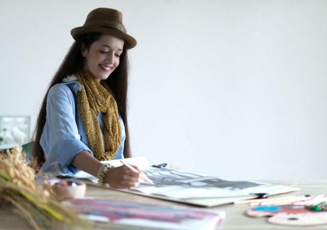 Smiling young female painter painting in her studio. Selective focus and small depth of field.